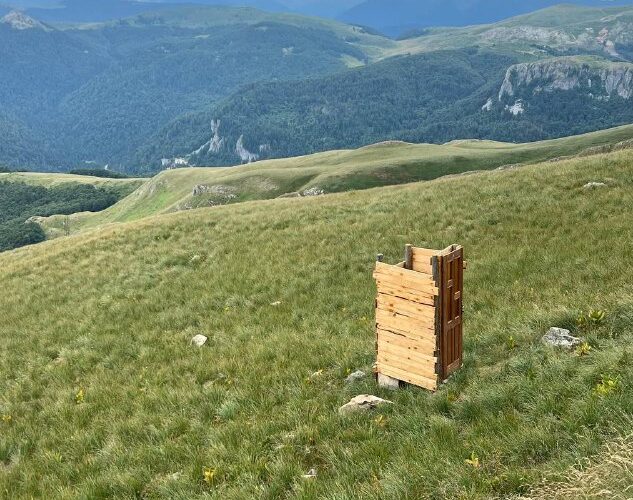 Открытая поляна в горах Черногории с деревянным строением, вид на природные красоты и облачное небо.