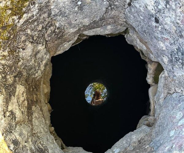 Углубление в скале на мероприятии в Черногории, вид сквозь отверстие с отражением природы и человека.